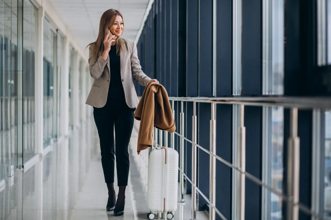 Eine Frau im stilvollen Outfit mit einem Koffer am Flughafen