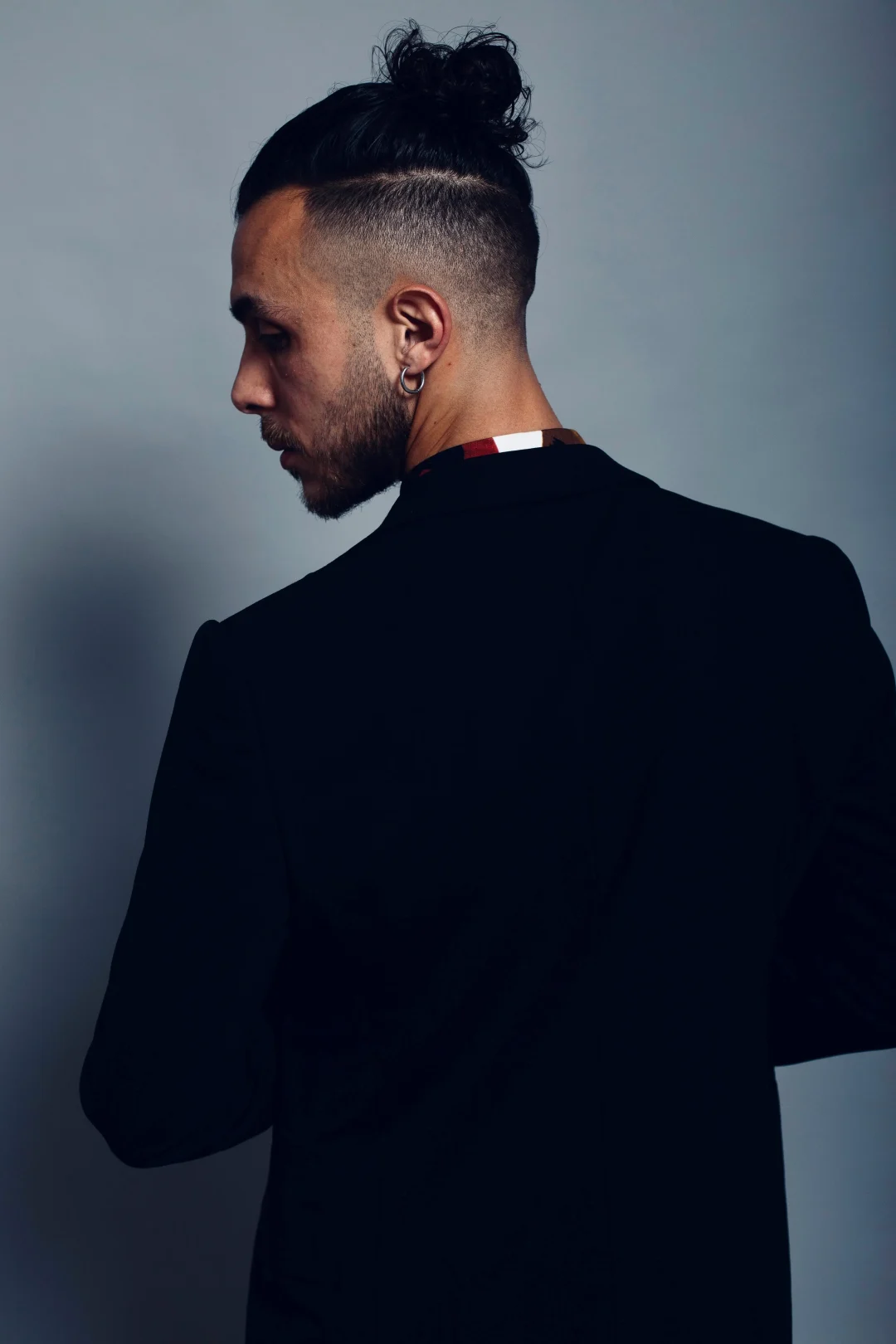Moderner Undercut 2026 mit Low Fade und Man Bun – eleganter Männerlook im schwarzen Sakko