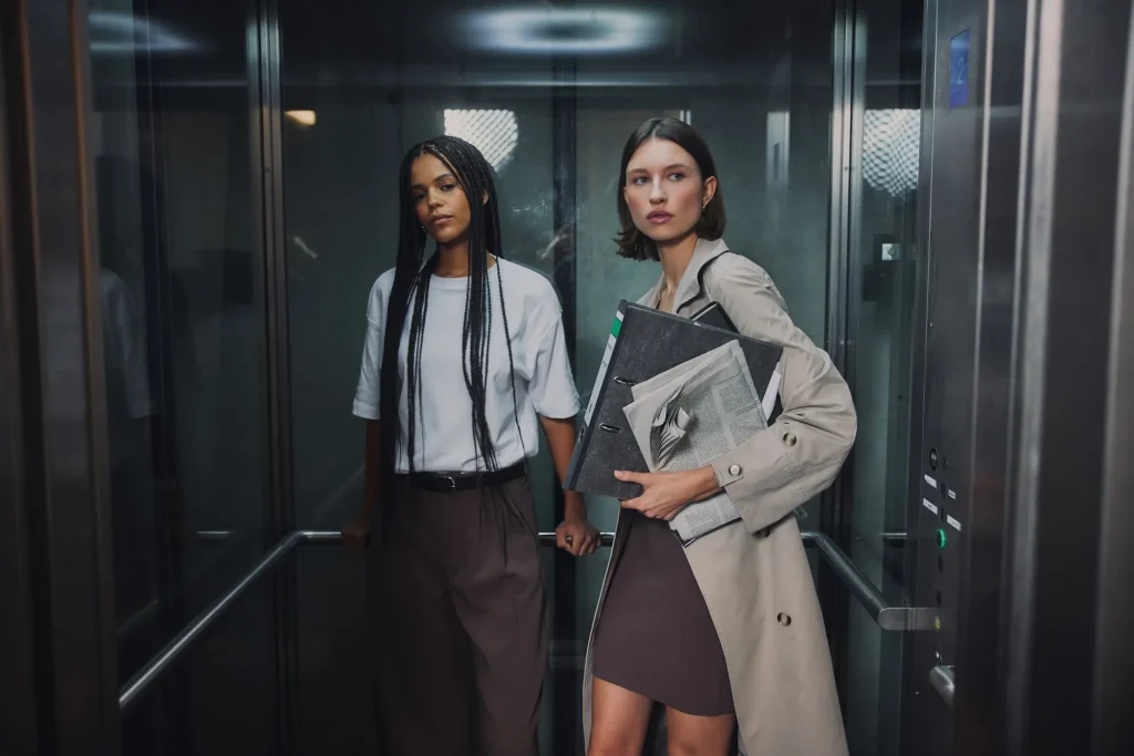 Zwei Models aus der Everly SS26 Kollektion im Aufzug mit minimalistischen Office-Looks.