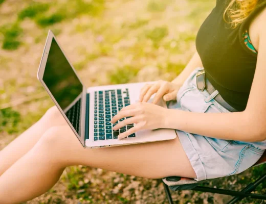 Frau arbeitet mit Laptop im Freien bei sonnigem Frühlingswetter