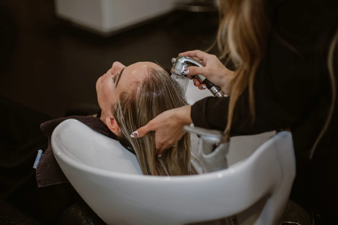 Friseurin wäscht Haare im Salon
