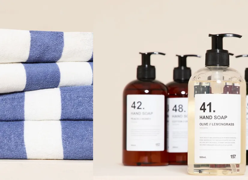 Gefaltete Handtücher in Blau und Weiß sowie Handseifen aus der Home-Kollektion von Lager 157 auf hellem Hintergrund.