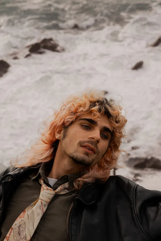Mann mit langen welligen Haaren im Stil der 70er-Jahre und modernem Retro-Look