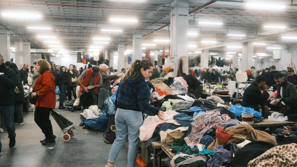 Besucher stöbern auf einem großen Second-Hand-Markt mit zahlreichen Kleidungsstücken und Verkaufsständen.