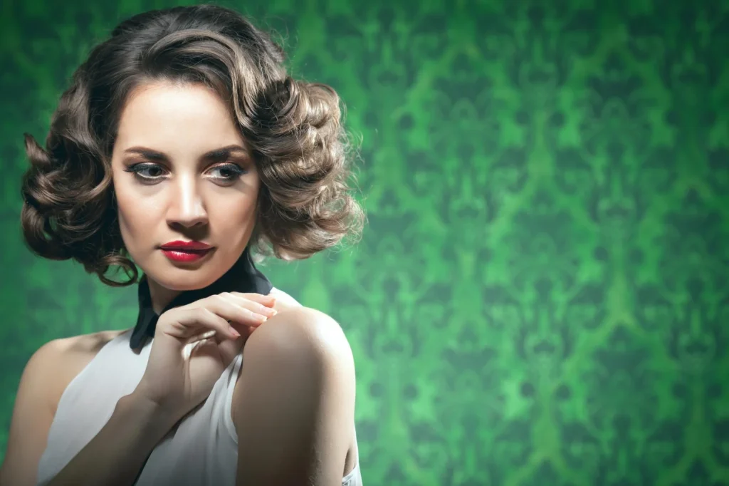 Frau mit voluminösem Retro-Bob und elegant geformten Wellen vor grünem Hintergrund