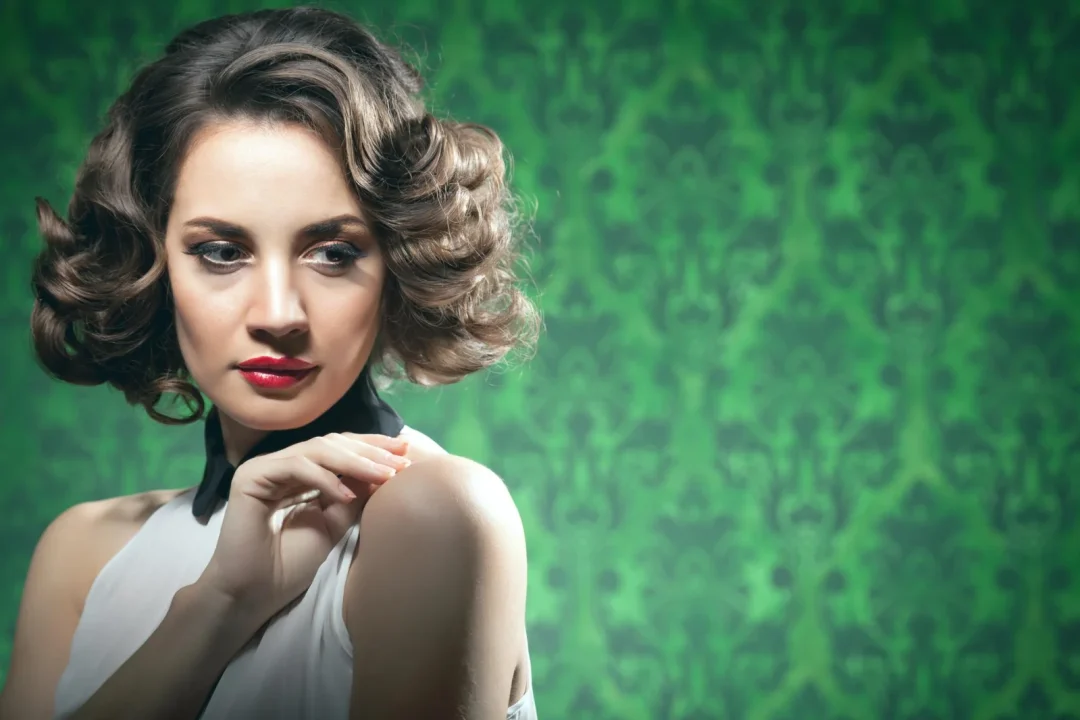 Frau mit voluminösem Retro-Bob und elegant geformten Wellen vor grünem Hintergrund