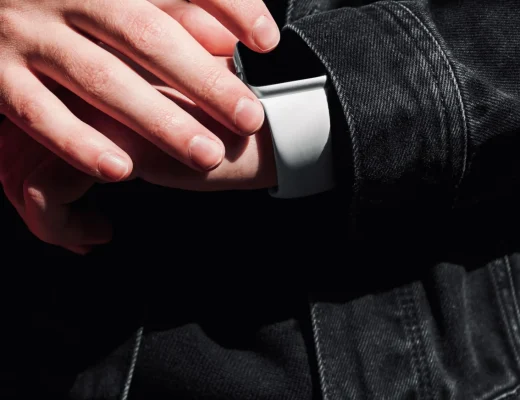 Hand in schwarzem Denimärmel mit Smartwatch, Detailaufnahme der Ärmelöffnung und Knopfleiste