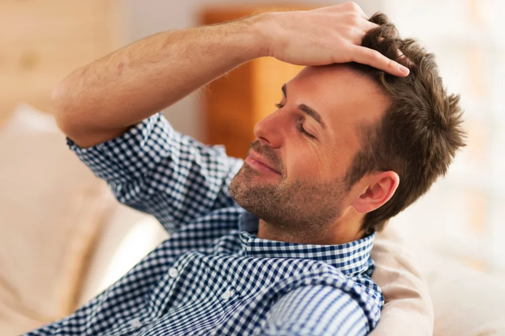 Mann fährt sich mit der Hand durch die Haare und zeigt seinen Haaransatz