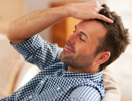 Mann fährt sich mit der Hand durch die Haare und zeigt seinen Haaransatz