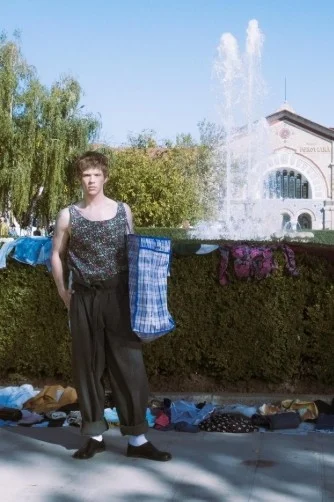 Model in weitem Hosen-Outfit vor einem Brunnen bei der Flohmarkt-Modenschau von Alexei Sorokin in Chișinău.