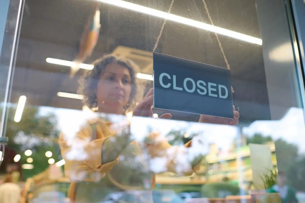 Symbolbild einer Mitarbeiterin, die ein Closed-Schild ins Schaufenster hängt – Galeria-Insolvenz 2026