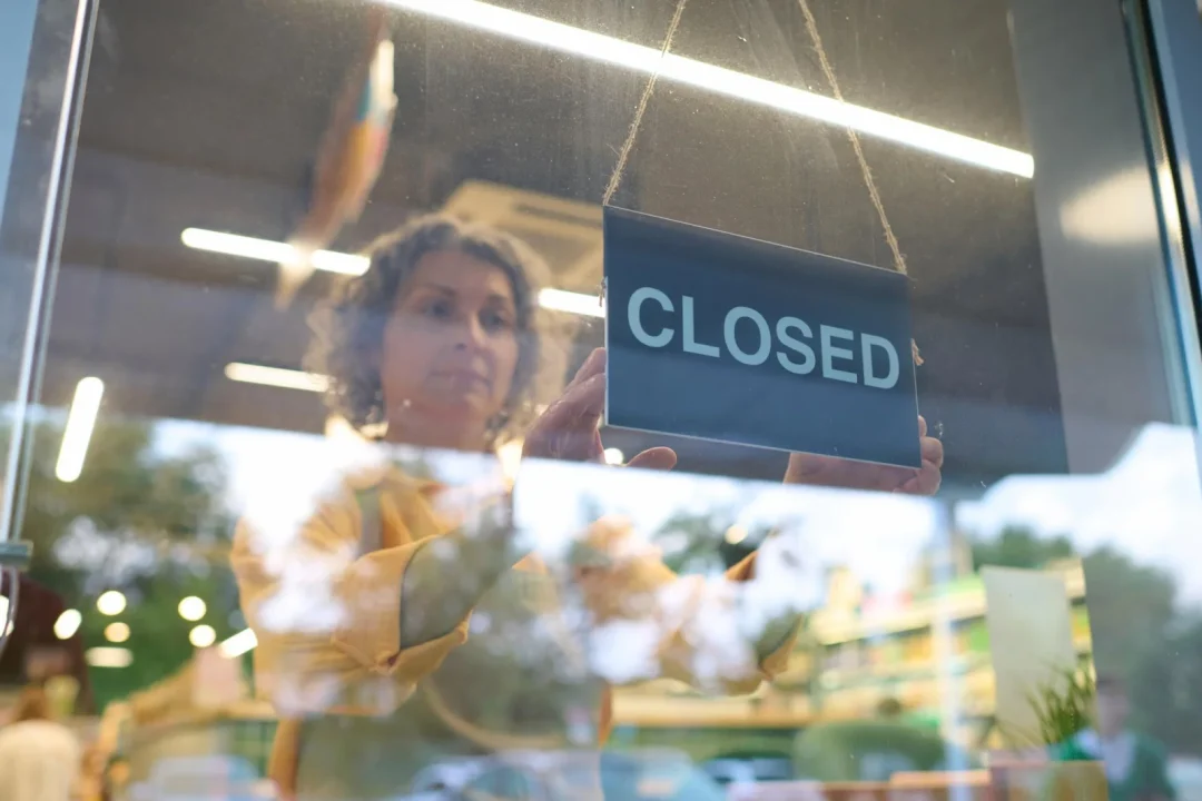 Symbolbild einer Mitarbeiterin, die ein Closed-Schild ins Schaufenster hängt – Galeria-Insolvenz 2026