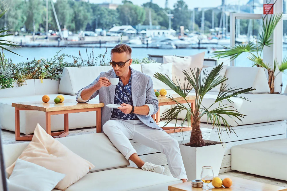 Mann genießt Kaffee auf einer eleganten Terrasse am Yachthafen als Ausdruck von Quiet Luxury