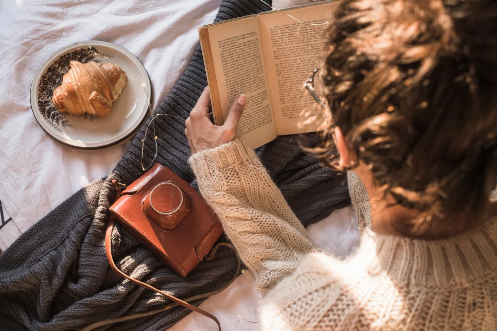 Gemütlicher Lesemoment mit Buch, Strickpullover und Croissant – Bücher für den Herbst 2026