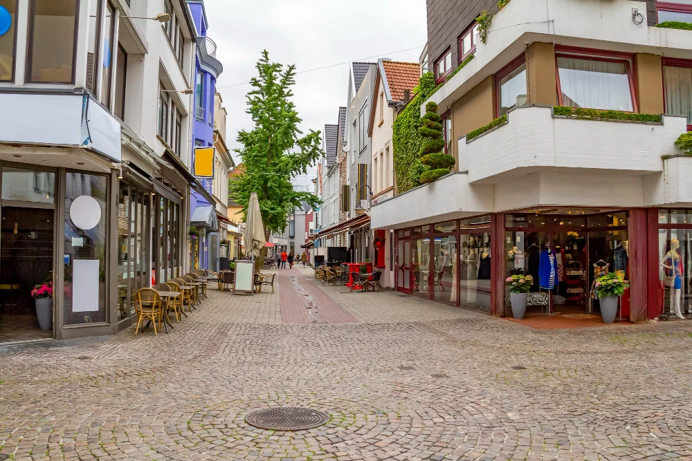 Fußgängerzone mit Modegeschäften, Schaufenstern und Außengastronomie in einer Innenstadt