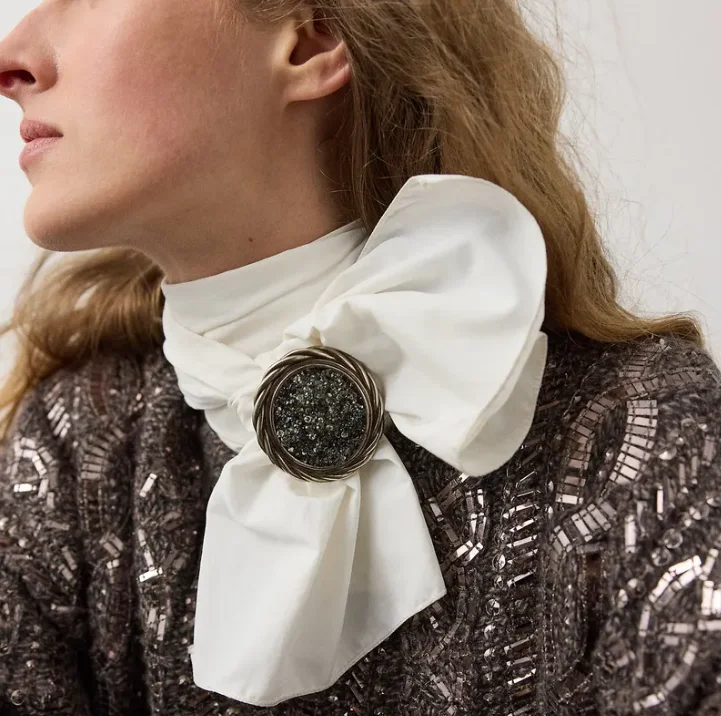 Große Brosche als Verschluss an einem weißen Schal zu einem eleganten Herbst-Look