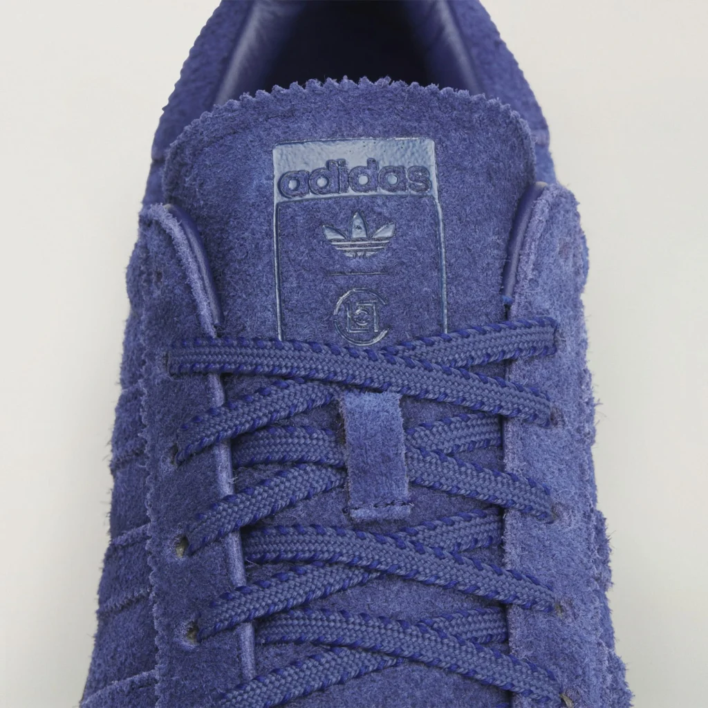 Nahaufnahme des blauen Adidas x CLOT Superstar von Edison Chen mit rauem Wildleder, blauen Schnürsenkeln und Adidas-CLOT-Logo auf der Zunge.