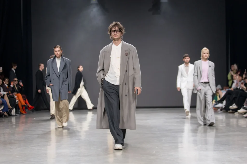 Models präsentieren moderne Herrenmode mit grauen Mänteln und eleganten Anzügen bei einer Modenschau der Moldovan Brands Runway 2026.