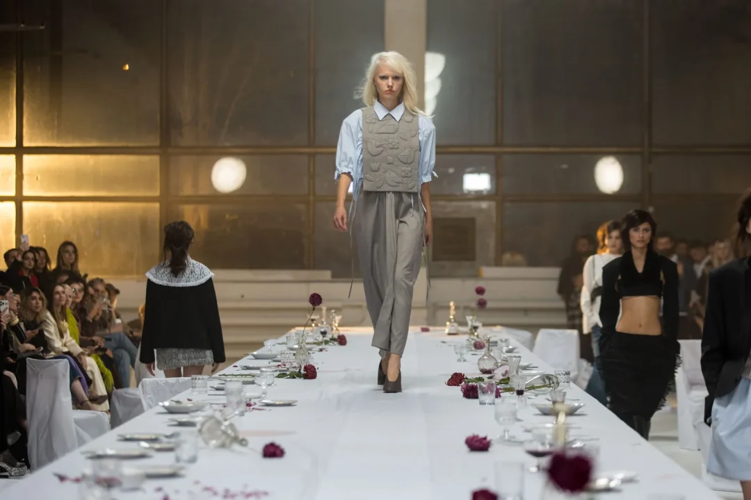 Model mit grauem Outfit auf einem langen, weiß gedeckten Laufsteg bei der Moldovan Brands Runway 2026 in Chișinău.