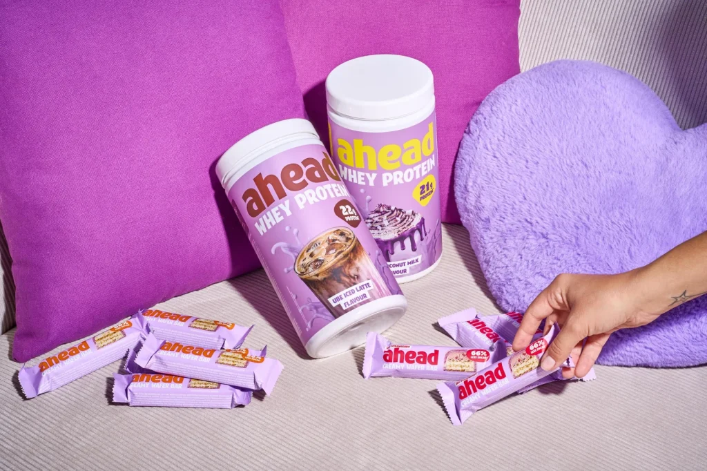 Vier neue ahead Ube-Produkte: Whey-Proteinpulver und Waffelriegel in violetten Verpackungen