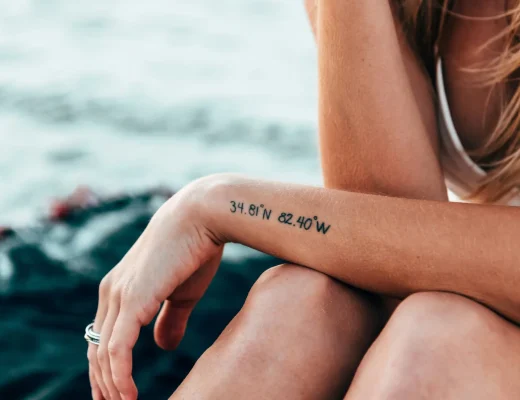 Frau mit einem kleinen Koordinaten-Tattoo am Unterarm