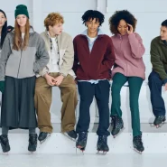 Uniqlo München – junge Menschen in Fleece- und Basics-Looks sitzen mit Eislaufschuhen auf einer Bank in heller Eishalle.