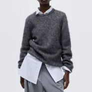 Grauer flauschiger Pullover über weißem Hemd, kombiniert mit grauer Bundfaltenhose – cleaner Herbst-Streetstyle-Look in Grau.