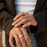 French Nails auf kurzen Nägeln: Nude-Basis mit geschwungener weißer Spitze, feinem Glitzer und dezenten Linien-Details.