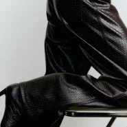 Dunkelbraune Lederhose mit strukturierter Oberfläche in Nahaufnahme, kombiniert mit dunklem Oberteil und Absatzschuh.