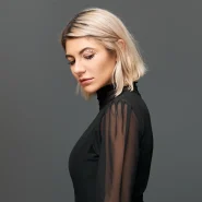 Blonde Person mit kinnlangem Blunt Bob und Seitenscheitel, moderner Bob-Schnitt mit klarer Linie vor neutralem Hintergrund