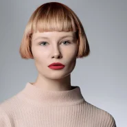 Micro Bob mit geradem Pony und klarer Linienführung bei einer Frau vor neutralem Hintergrund