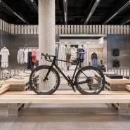 Ein stylisches Fahrrad auf einem Holztisch inmitten eines modernen Geschäftslokals mit Herrenbekleidung