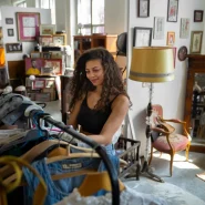 Eine junge Frau durchstöbert Second-Hand-Kleidung auf einer Plattform