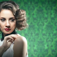 Frau mit voluminösem Retro-Bob und elegant geformten Wellen vor grünem Hintergrund