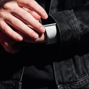 Hand in schwarzem Denimärmel mit Smartwatch, Detailaufnahme der Ärmelöffnung und Knopfleiste