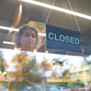 Symbolbild einer Mitarbeiterin, die ein Closed-Schild ins Schaufenster hängt – Galeria-Insolvenz 2026